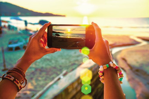 Person taking photo of beach on smartphone