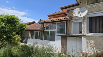 Close-up view of garden with tall grass and white framed windows of the Bulgarian house.