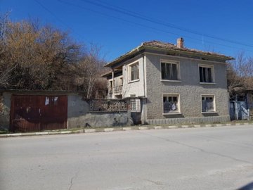 Front view of a two-storey house with a tiled roof and textured walls in Nikolaevo village
