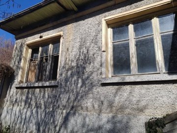 Close-up view of textured exterior wall with two large windows casting shadows