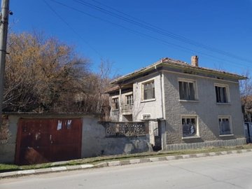 Two-storey house with balcony and garage door on a quiet street in Nikolaevo village