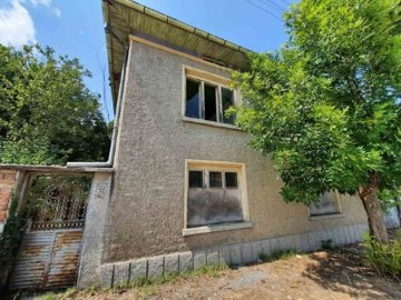 Side view of two-storey house with textured walls and surrounding trees