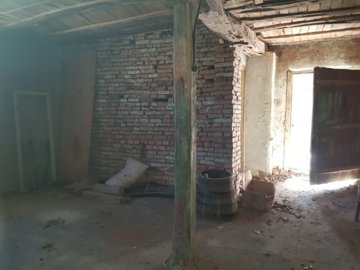 Room interior showing exposed brick wall, wooden beams, and an open door with sunlight