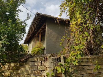 View of the house corner featuring a traditional wooden balcony and a brick wall below