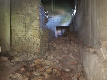 Interior room showing brick walls and a large pile of bricks scattered on the floor