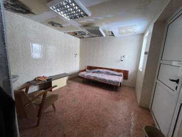 Indoor room featuring tiled floor and walls, a single bed, and chairs arranged inside.