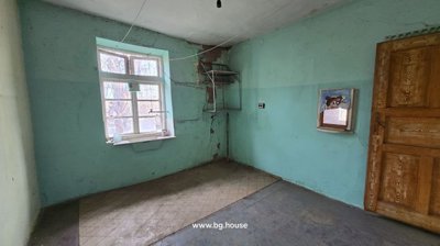 Room with turquoise painted walls, a single window, wooden door, and metal wall shelves.
