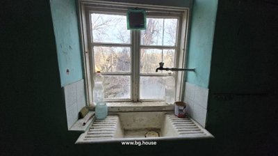 Window with a white ceramic sink beneath it and plastic bottles placed on the windowsill.