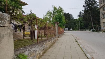 Side street view showing a fenced garden and sidewalk adjacent to a single-storey house