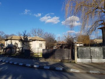 Garden area behind a single-storey house with a tiled roof, showing bare trees and open ground
