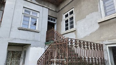 View of the house exterior showing a metal staircase leading to an upper entrance and several windows with white frames.