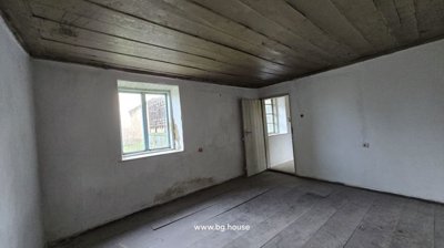 Interior view of an empty room featuring a wooden ceiling, white walls, wooden floor, and a window.