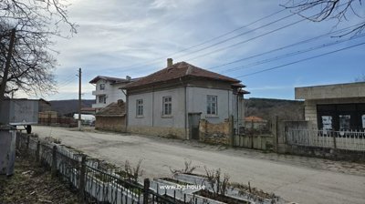 Street view showing a stone and brick house with a tiled roof and nearby buildings in the village.