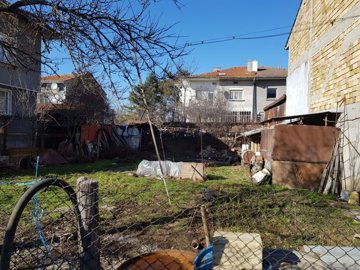 View of fenced grassy building land with garden structures and bare trees in Popovo, Bulgaria