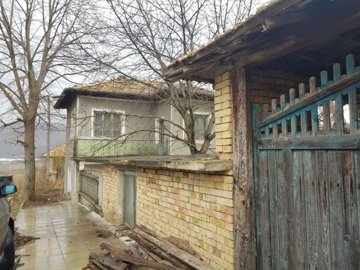Image showing the brick wall and old wooden gate with the two-storey house in the background