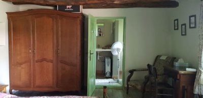 Bedroom featuring wooden wardrobe, armchair, desk and green door opening to bathroom