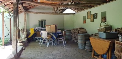 Covered outdoor space with wooden beams, stone floor, table and stacked firewood