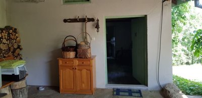 Covered area with white walls, wooden cabinet, baskets and stacked firewood