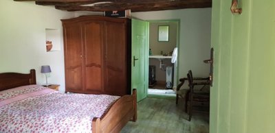 Bedroom with wooden furniture and green door revealing bathroom with basin and fan