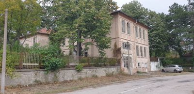 View showing the building's side wall, trees, and a car parked nearby
