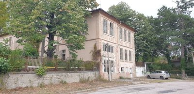 Building exterior with trees and a car parked on the road beside it