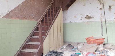 Wooden staircase with worn steps and damaged wall surfaces inside the building