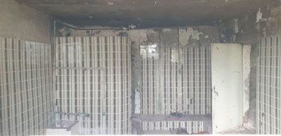 Room featuring white vertical wall tiles and signs of wear and damage on ceiling and walls