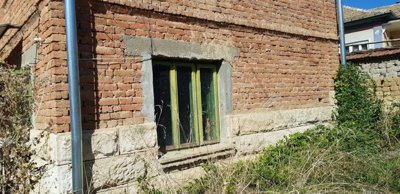 Close-up of a ground floor window with green frame set in brick and stone wall