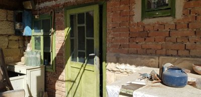 Green door and window with glass panes beside an outdoor table holding various household items
