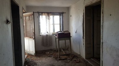 Interior corridor with a window covered by a sheer curtain and multiple doorways leading to other rooms.
