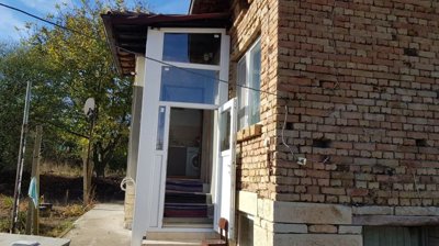 Entrance to house showing white enclosed porch and stairs leading inside