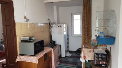 Room inside the house showing a microwave on a table, refrigerator, and a birdcage mounted on the wall