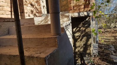 Side view of concrete stairs supported by columns with garden area in the background