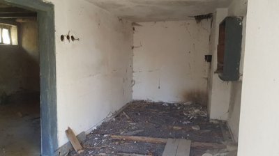 Room interior with white walls and a small window opening, showing signs of wear and damage