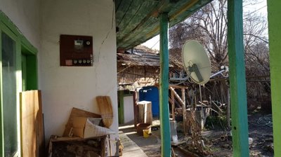 Outdoor covered space featuring green wooden beams, a satellite dish, and assorted stored items