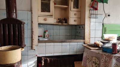 Kitchen area showing a brown stove, tiled walls, and wooden cabinets with kitchen items.