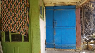 Porch area showing a green door, blue door, and a colorful woven textile hanging on the wall