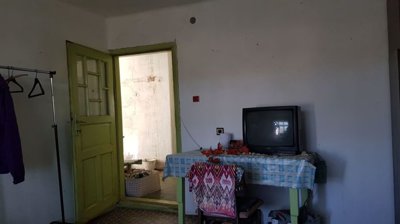 Room interior showing a green door, table with cloth, and an old television set on top