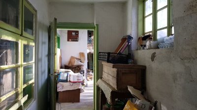 Corridor inside the house showing green window frames, various household items, and a cat on the windowsill