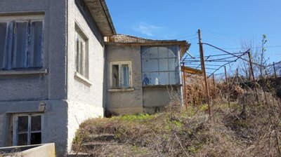 Side perspective of the house featuring a glassed-in porch and windows under a tiled roof