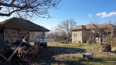 Spacious garden area featuring rustic buildings, outdoor seating, and natural vegetation
