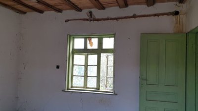 Empty interior room showing green painted window and door frames, white walls, and wooden ceiling