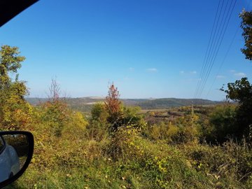 Scenic view of countryside hills and trees under a clear blue sky
