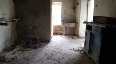 Interior room showing concrete floor, old wooden furniture, and open doorways to adjacent spaces