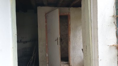 Interior view of a small room featuring a stone sink and doorway leading outside