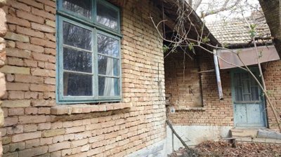 Close-up view of a brick house wall featuring a window and a blue door