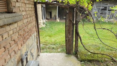 View from the porch through a wooden gate into the garden area with stone walls and greenery