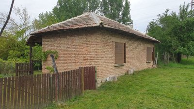 Side perspective showing brick walls, wooden shutters, and a wooden fence enclosing part of the garden