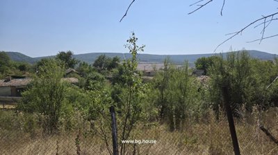 View over trees and rooftops towards hills in the distance under a clear blue sky