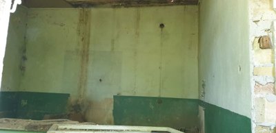 Interior view of an empty room with green and white painted walls and some exposed brickwork